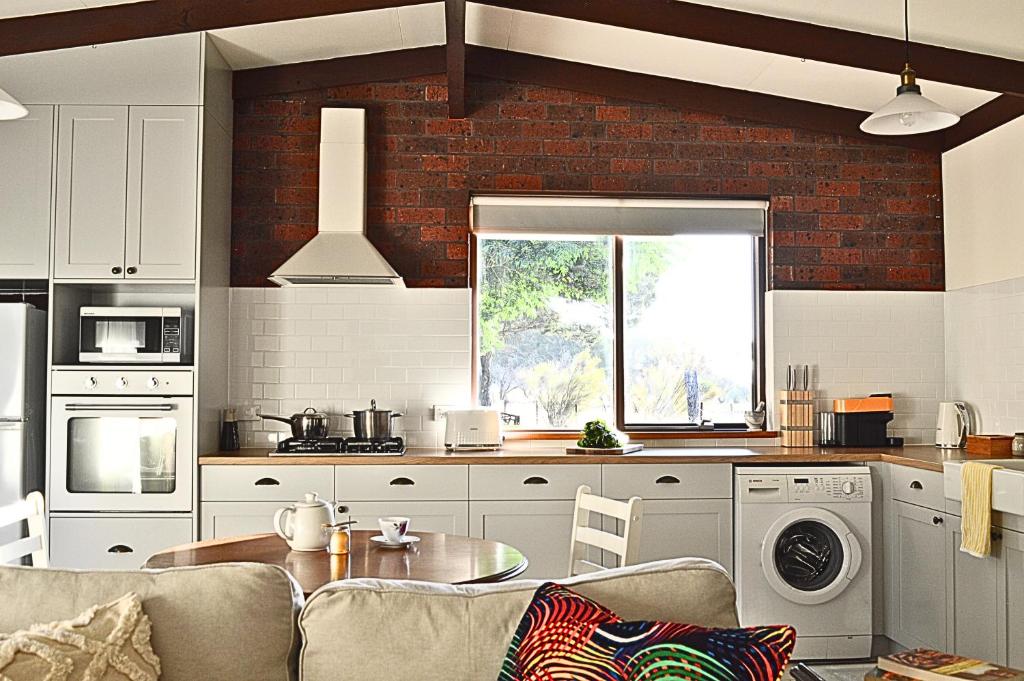 a kitchen with white cabinets and a brick wall at UzuriBarossa in Altona