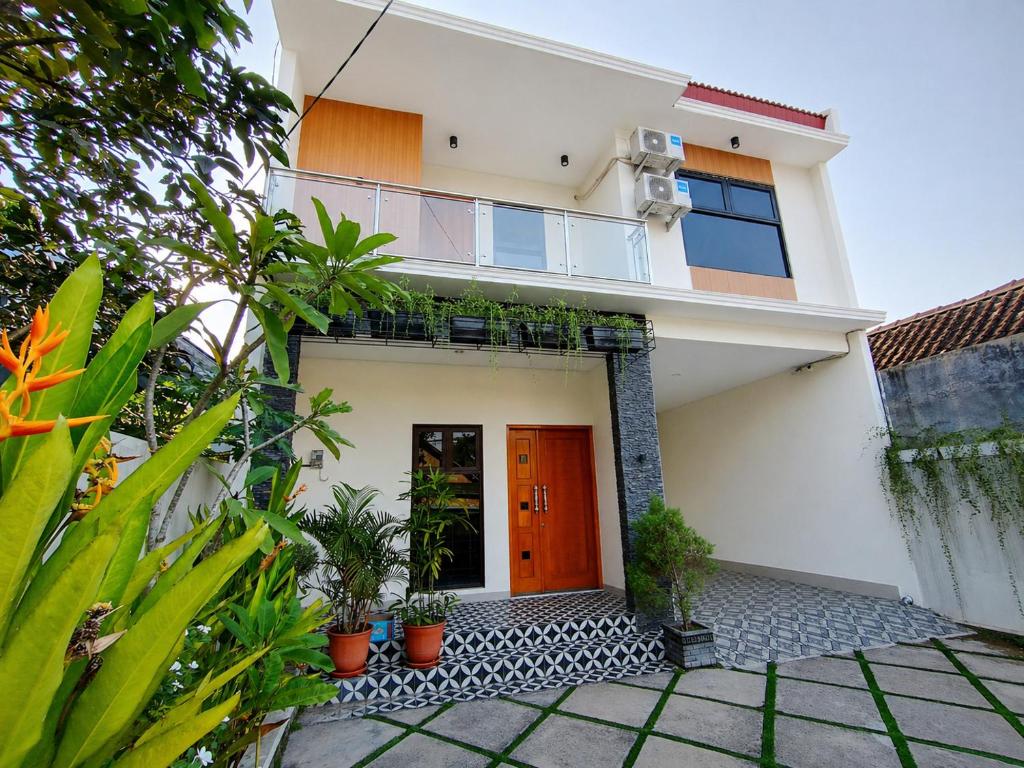 a house with a red door and some plants at Griya Anindita in Sumberrejo