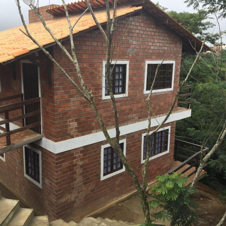 a brick house with white windows and a tree at Casa no centro de Serra Negra in Bezerros