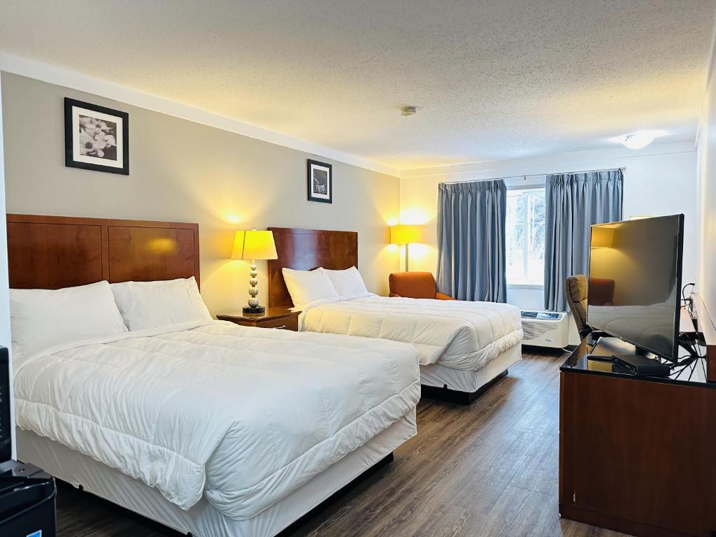 a hotel room with two beds and a flat screen tv at Sunset Inn & Suites in Sioux Lookout