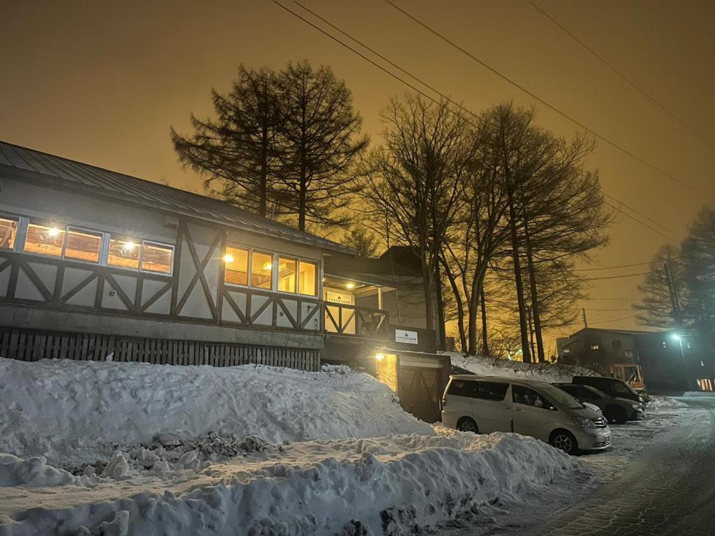 a car parked in front of a house covered in snow at Yamadasan Ski Lodge - Madarao in Madarao Kogen