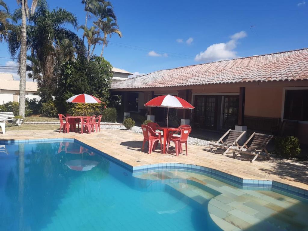 a pool with chairs and umbrellas next to a house at Recanto Praia Peruibe in Peruíbe