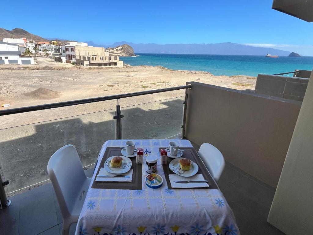 a table with food on a balcony with a view of the ocean at MonteCara View T1 in Mindelo