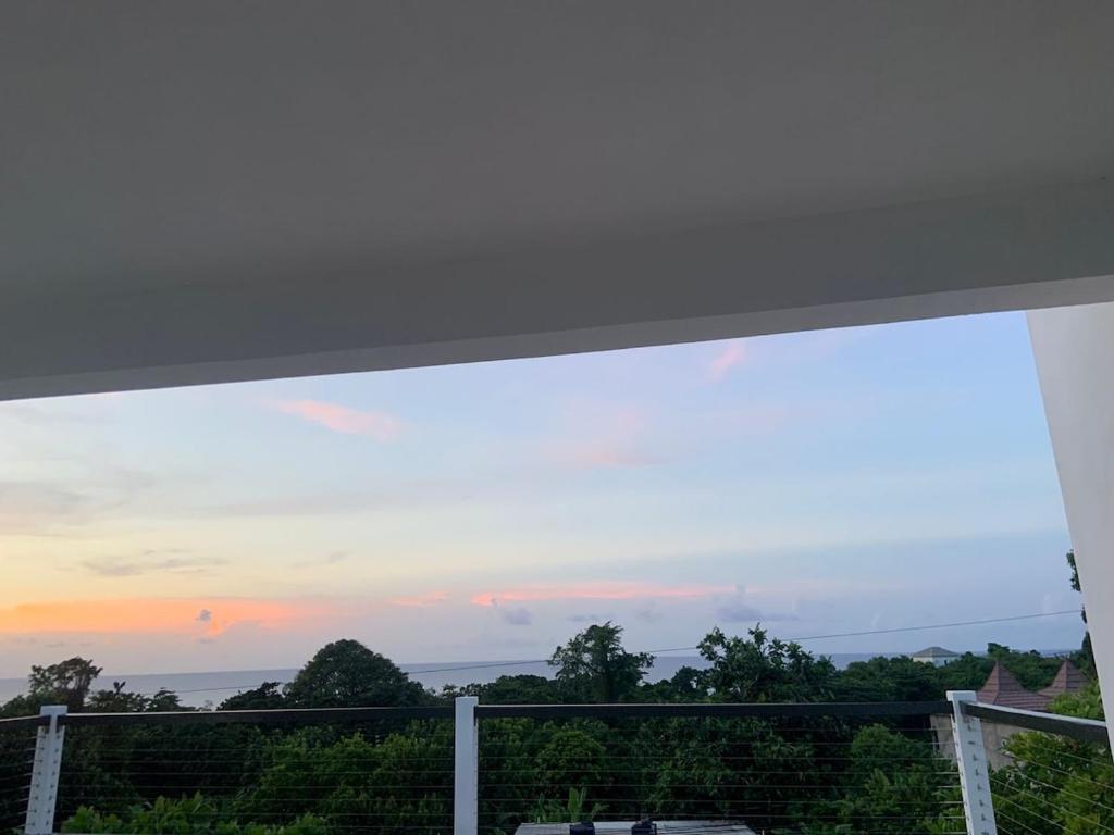 a view of the sunset from the balcony of a house at Purevibe Villa Portland Jamaica - Ocean view suite in Port Antonio