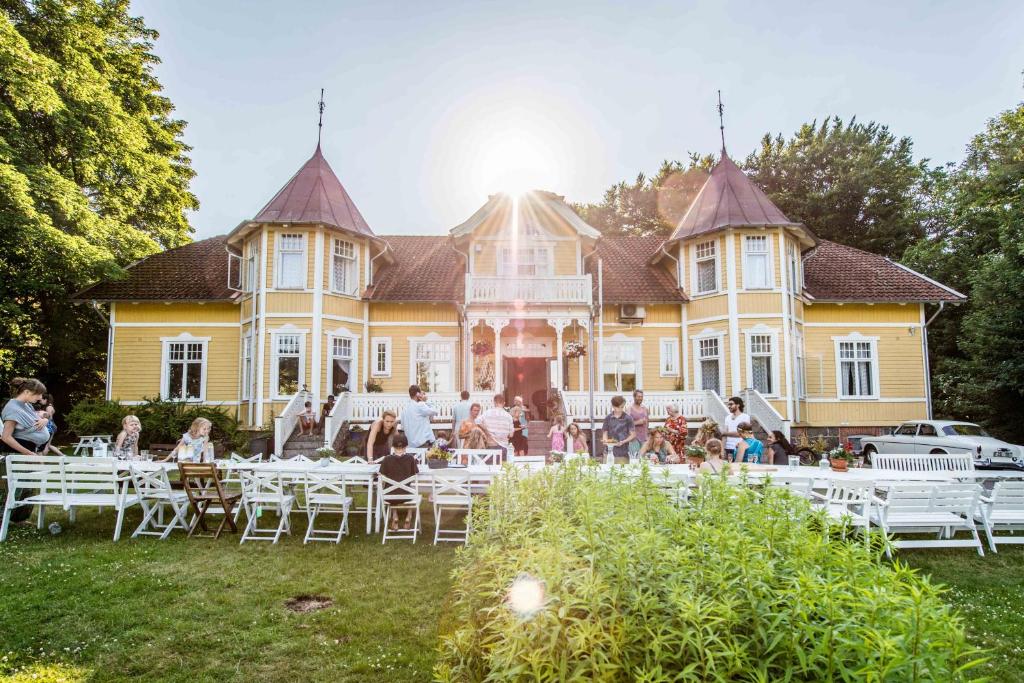 a group of people sitting at tables in front of a house at STF Villa Söderåsen B&B in Röstånga