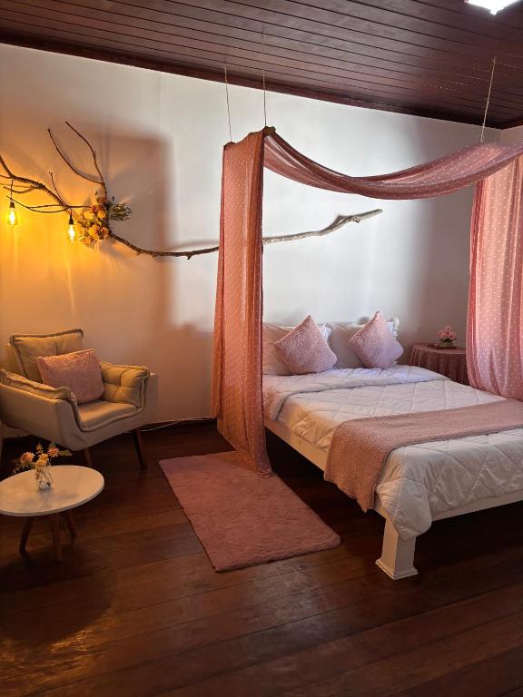 a bedroom with a canopy bed and a chair at Hospedagem Flor de Alissah in Arraial do Cabo