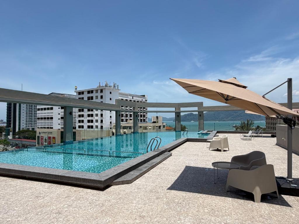 a pool on top of a building with an umbrella at PureJoy Hotel Langkawi in Kuah