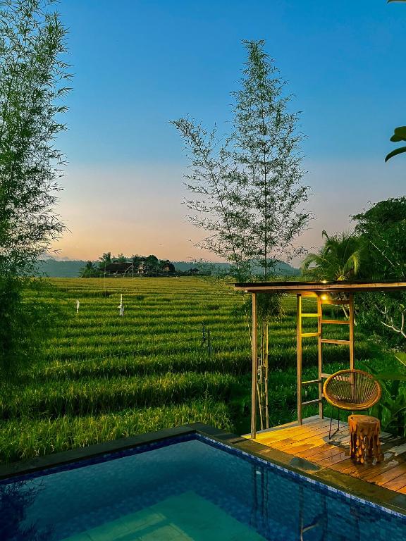 a pool with a table and a chair next to a field at The SUN House in Balian