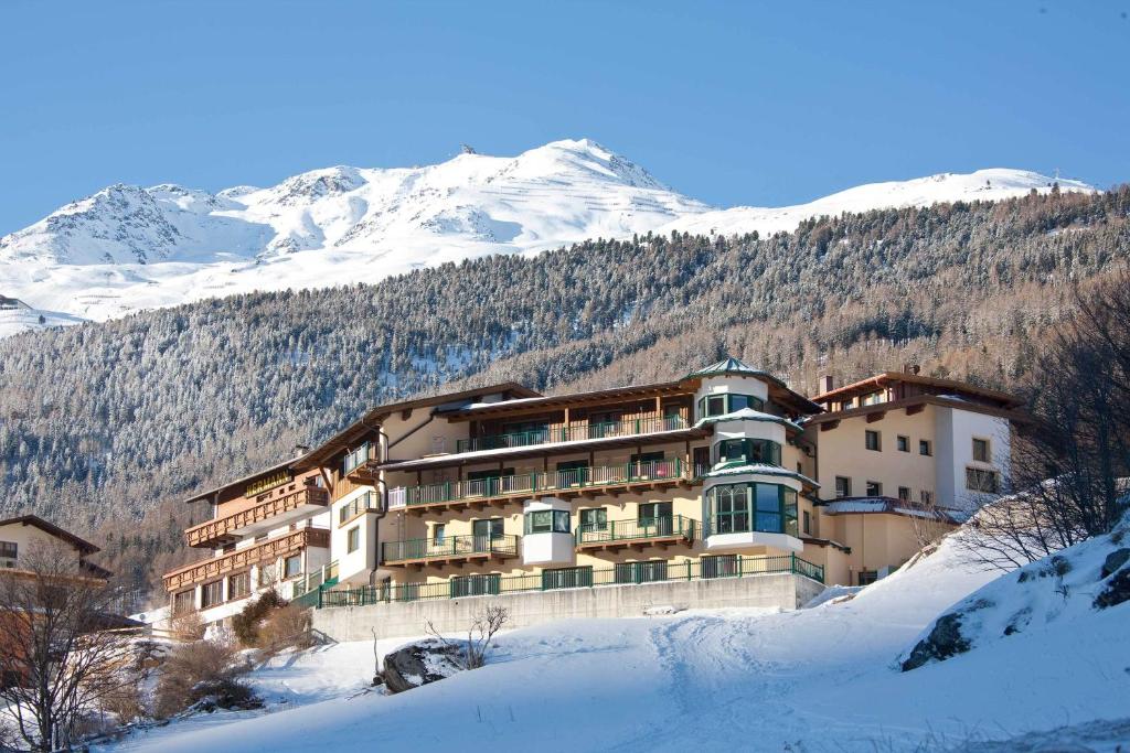 un grand bâtiment dans la neige avec une montagne dans l'établissement Alp Resort Tiroler Adler, à Sölden