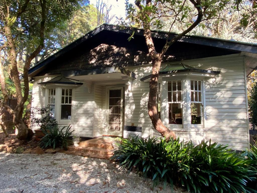 a white house with trees in front of it at Lochiel Cottages - Dandenong Ranges Escape in Olinda