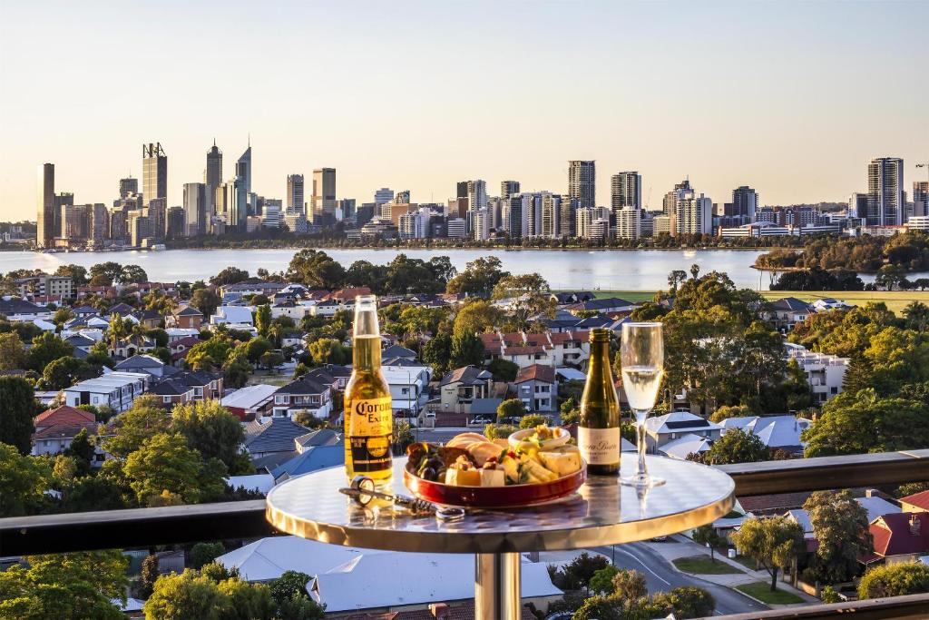 a table with bottles and glasses of wine and a bowl of fruit at Metro Hotel Perth in Perth