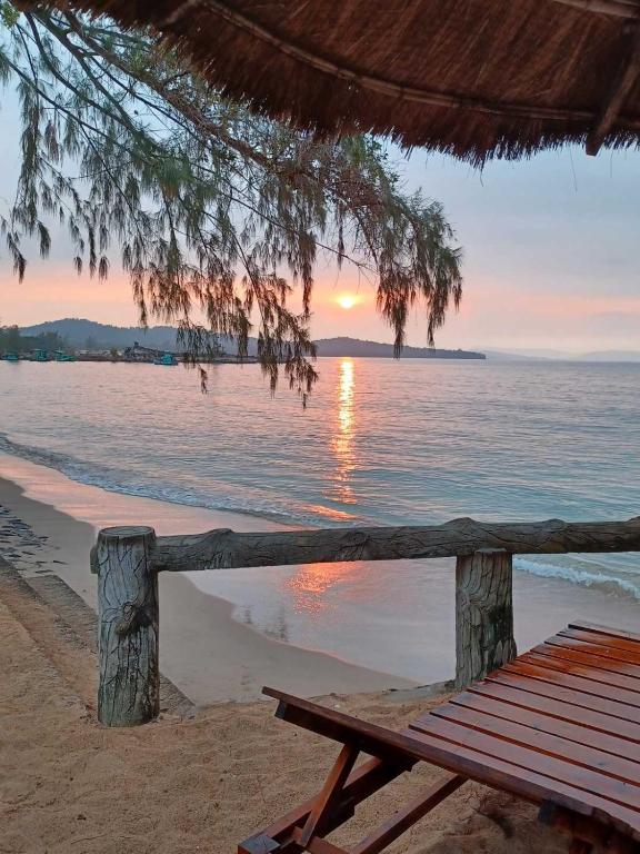 a picnic table on the beach with a sunset at Bamboo Cottages in Phú Quốc