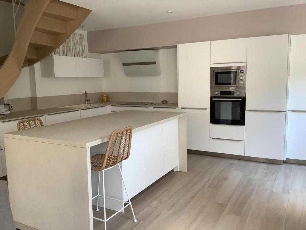 a kitchen with white cabinets and a counter with chairs at La maisonnette de colette in Chastel-Nouvel