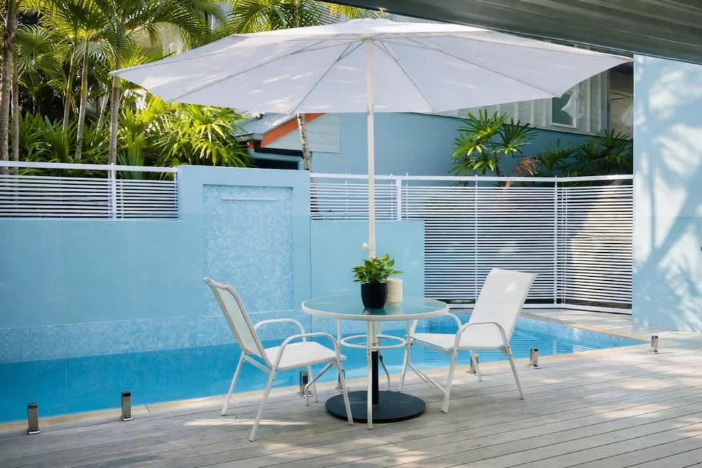 a table and chairs with an umbrella next to a pool at Villa 8 on Murphy Prime Location & Lifestyle in Port Douglas
