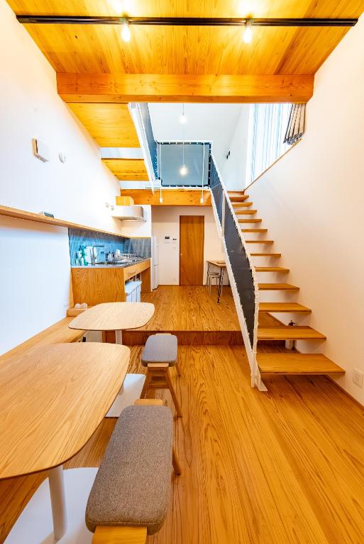a room with wooden floors and stairs and tables at いなぎの木箱 in Zentsuji