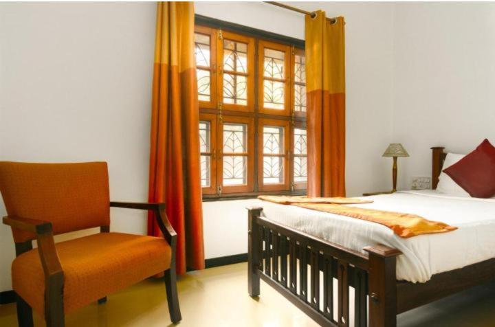 a bedroom with a bed and a chair and a window at Mahadev grand in Tirupati