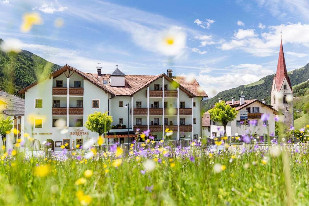 un village avec un champ de fleurs devant un bâtiment dans l'établissement Hotel Rosental, à Luson