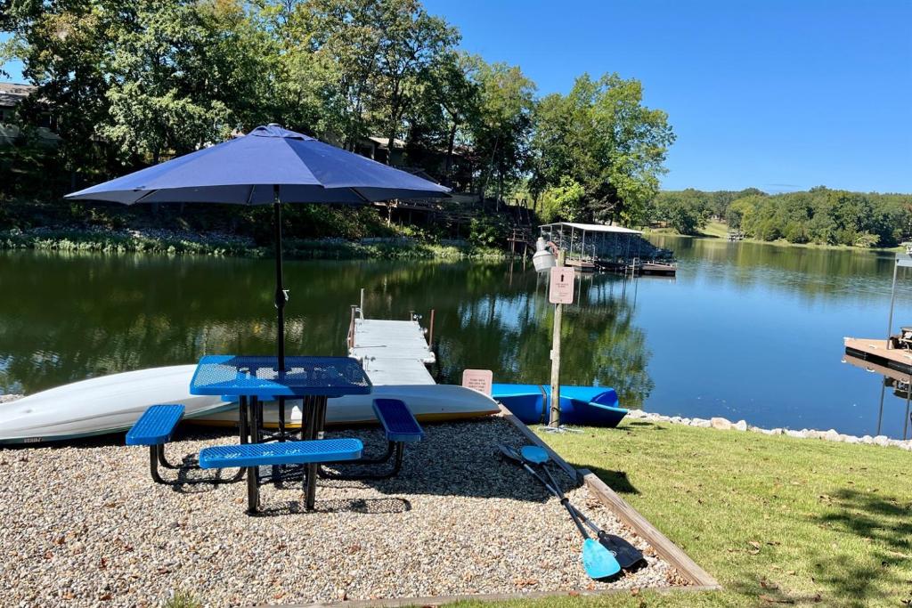 a picnic table with an umbrella next to a lake at Lakefront Suite Dock, No-Wake Cove & Firepit in Marion