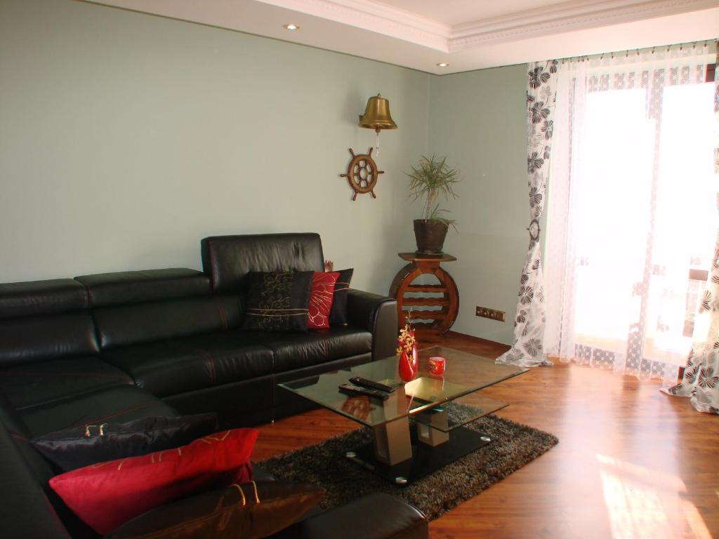 a living room with a black leather couch and a table at Apartments Vysoké Tatry in Vysoke Tatry - Horny Smokovec