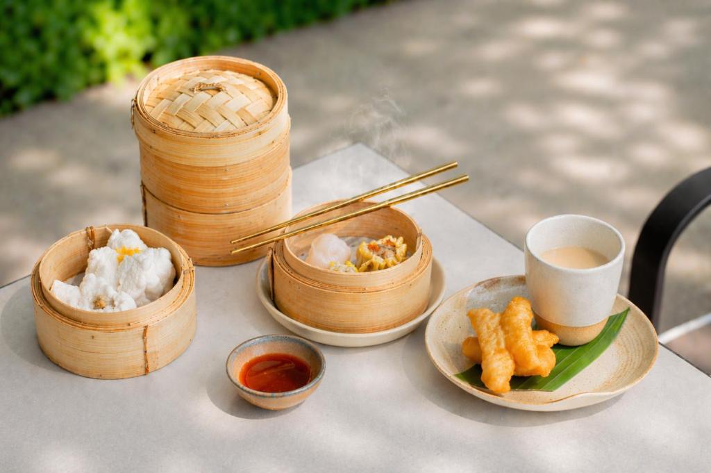 Dim sum and tea served outdoors at a shaded table.