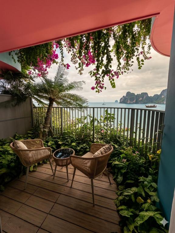 a patio with chairs and a tree with pink flowers at Flamingo Cát Bà Sea Residence , Sky Villa Premier Ocean View King Bed in Hai Phong