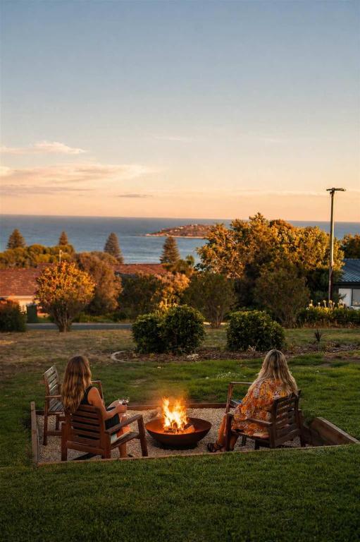 two women sitting in chairs around a fire pit at Ocean Views Byron Infused Bliss NEW in Encounter Bay
