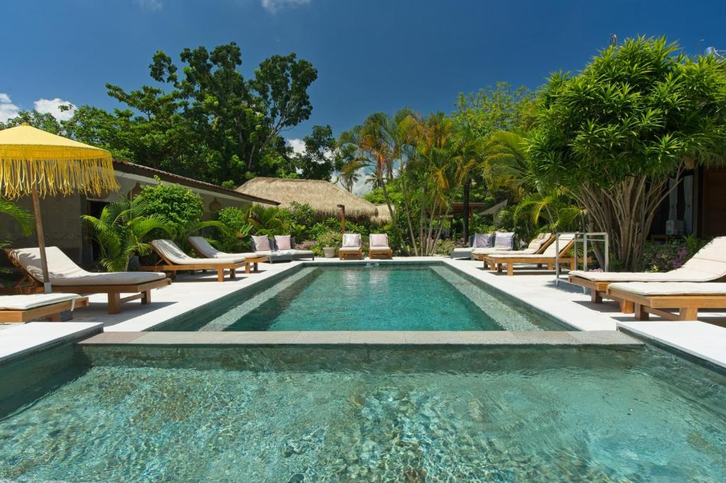 a swimming pool with chaise lounges and chairs at Gili Air Bungalows in Gili Islands