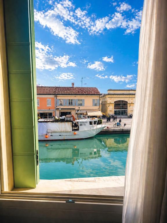a window with a view of a boat in the water at La Finestra sul Porto in Cesenatico