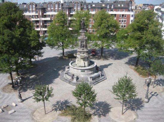 a large fountain in a park with trees and buildings at Gästezimmer am Hansaplatz in Hamburg