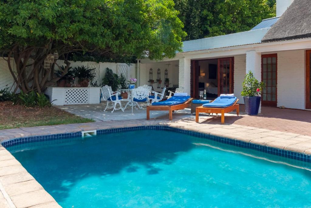 a swimming pool with two chairs and a house at The Garden View Suite in Franschhoek