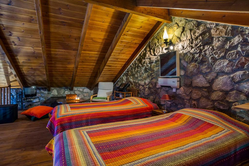 a bedroom with two beds and a stone wall at Naiades Village in Polydrossos