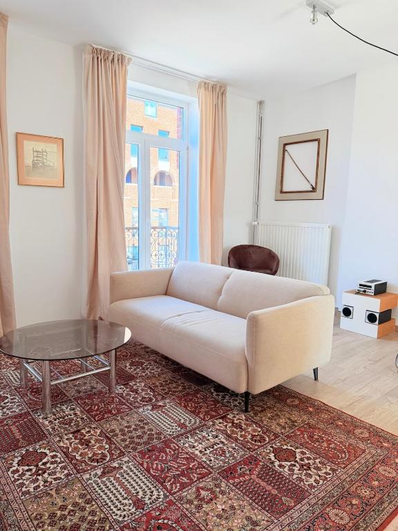 a living room with a white couch and a table at TRIPLEX 2 chambres Cosy à MONS in Mons