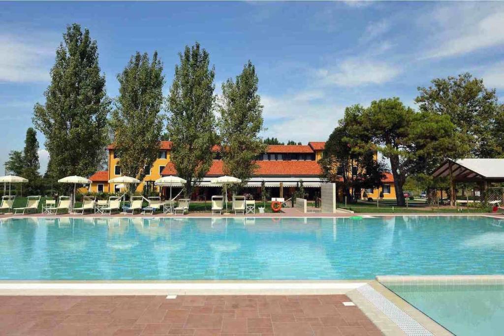 a large swimming pool with chairs and umbrellas at Dune Agriturismo in Eraclea Mare