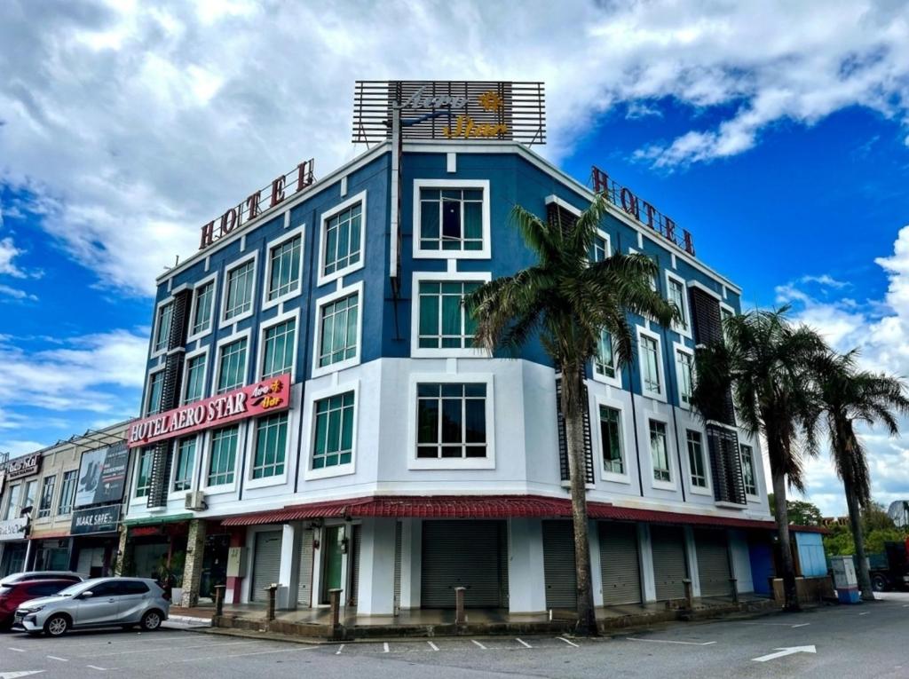 a blue and white building with palm trees in front of it at AERO Star Hotel in Seremban
