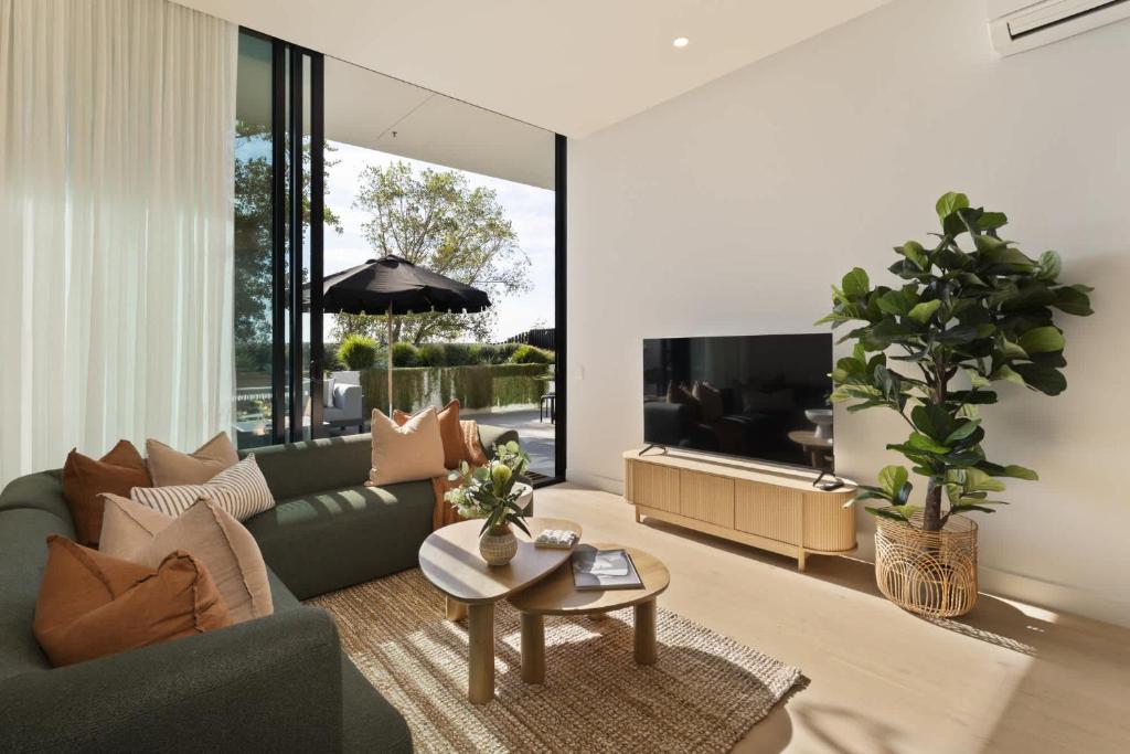 a living room with a green couch and a tv at Azure Horizon - Bay Views & Rooftop Spa in Frankston