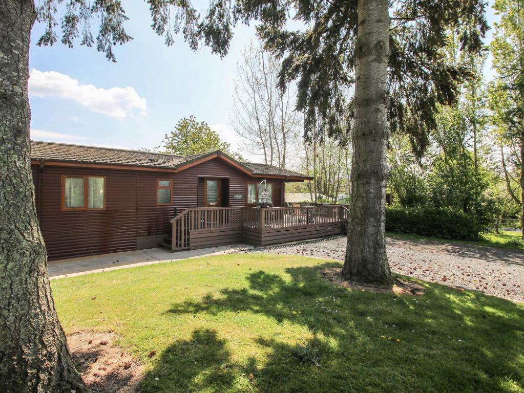a log cabin with a porch and two trees at Foxglove in Leominster