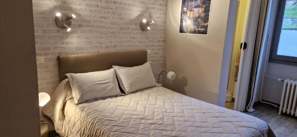 a bedroom with a bed with white sheets and pillows at Le Faubourg in Figeac