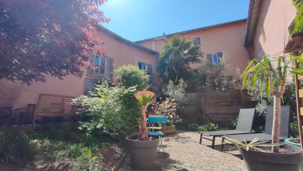 a courtyard with a house with a bench and plants at La Chamade en Beaujolais in Anse