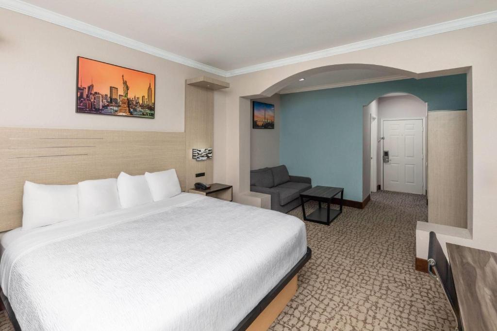 a hotel room with a white bed and a chair at Baymont by Wyndham Texas City in Texas City