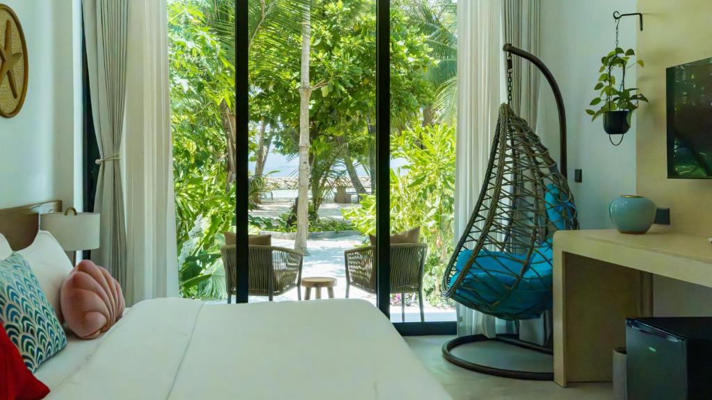 a bedroom with a bed and a large window at Biosphere Beach in Dharavandhoo