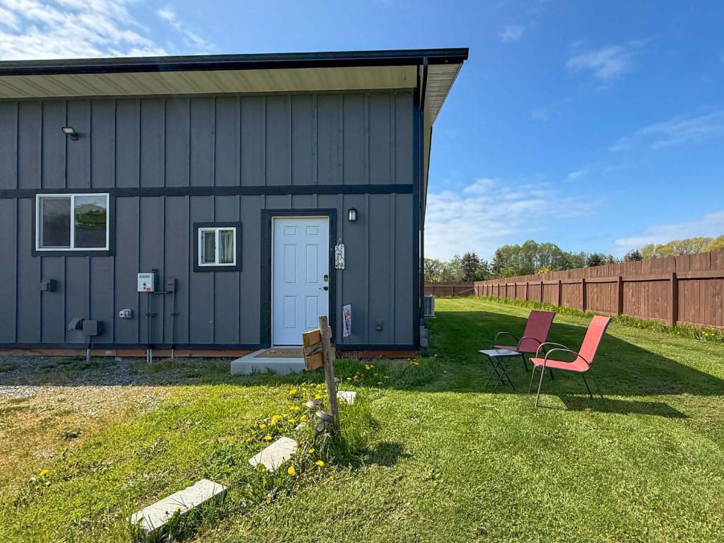 a barn with two chairs sitting in the grass at Cozy Pine Getaway in Sequim