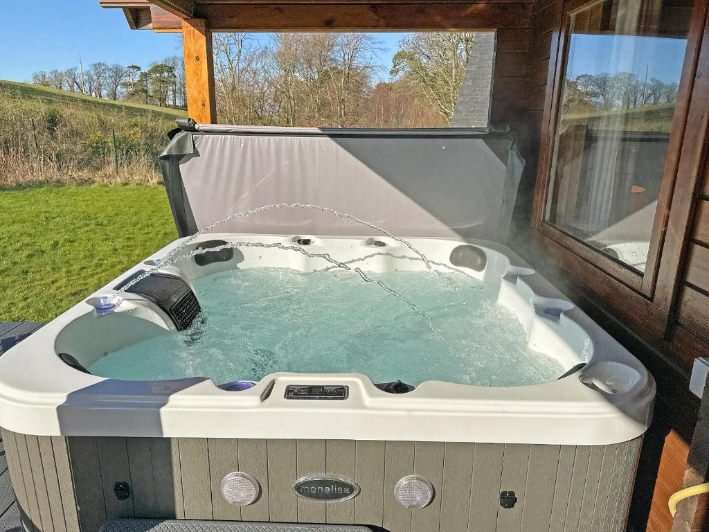 a jacuzzi tub sitting in a yard at Sun Rise Lodge No 10 - Hw7655 in Llanbedr
