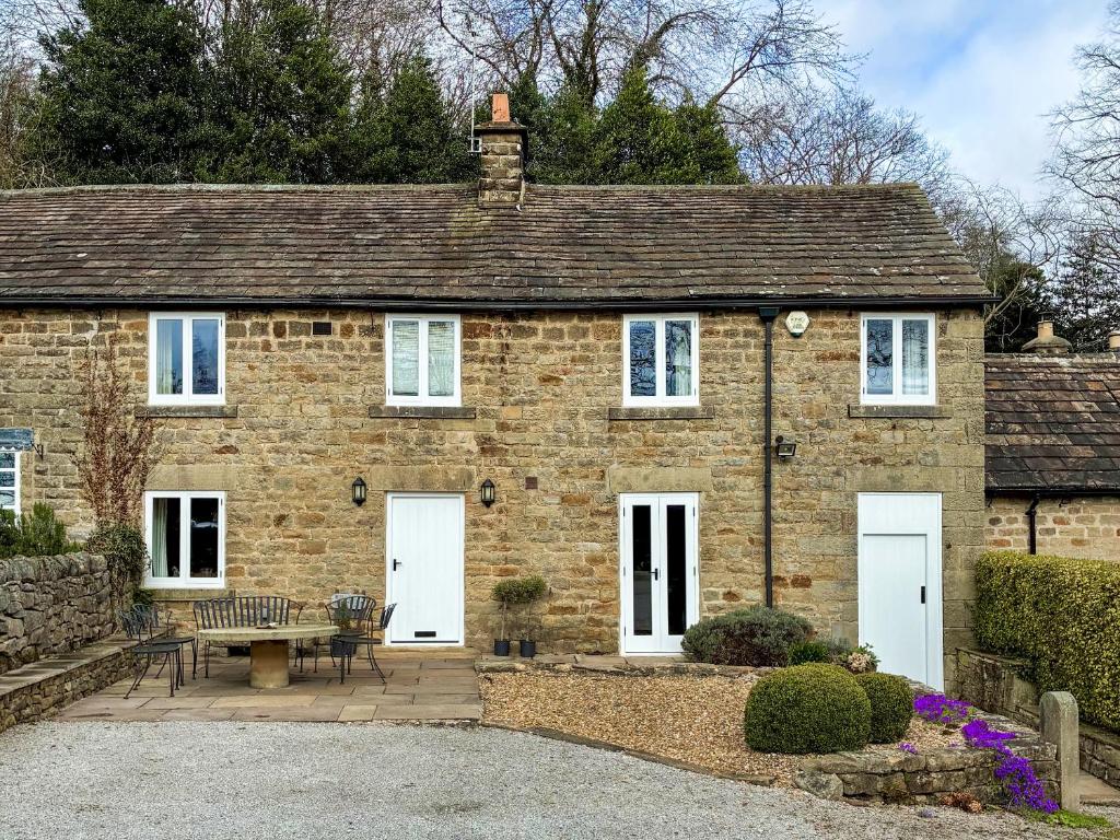 a brick house with white doors and a bench at Bank Cottage in Grindleford Bridge