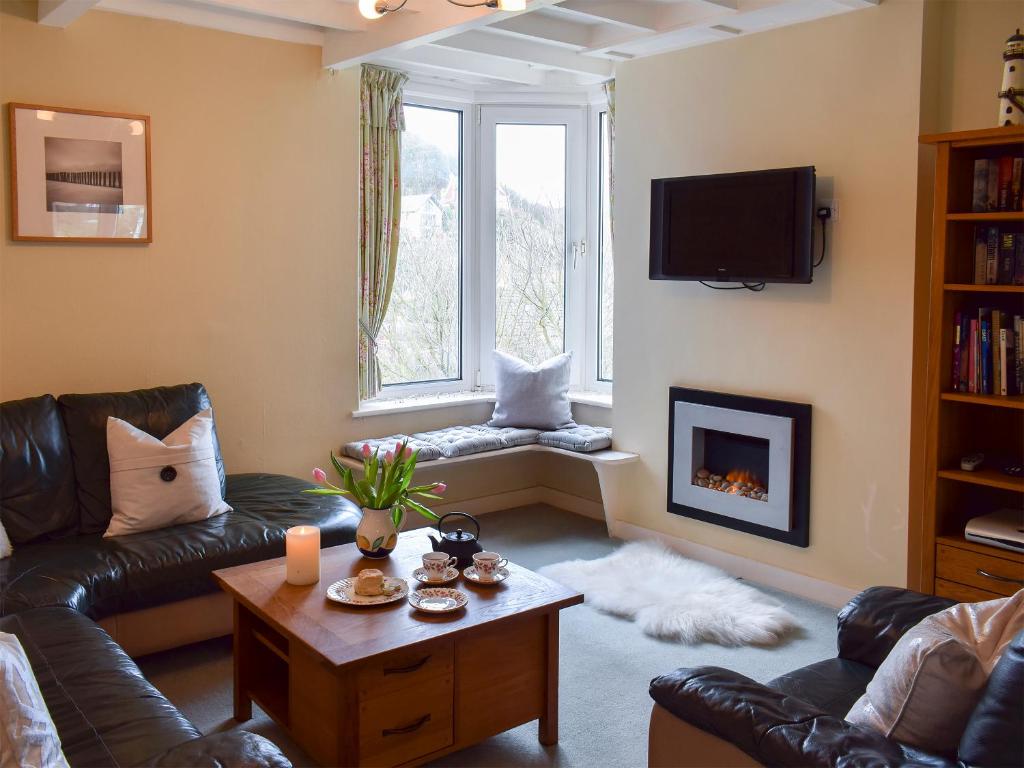 a living room with a leather couch and a fireplace at Puzzle Corner in Sandsend