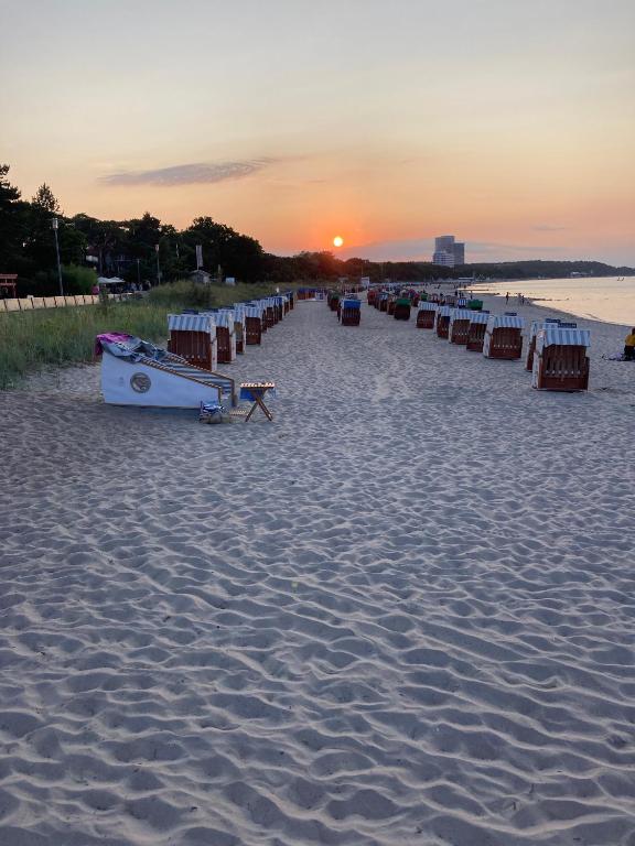 a row of beach chairs on a sandy beach at sunset at Schlafstrandkorb Nr 8 in Timmendorfer Strand