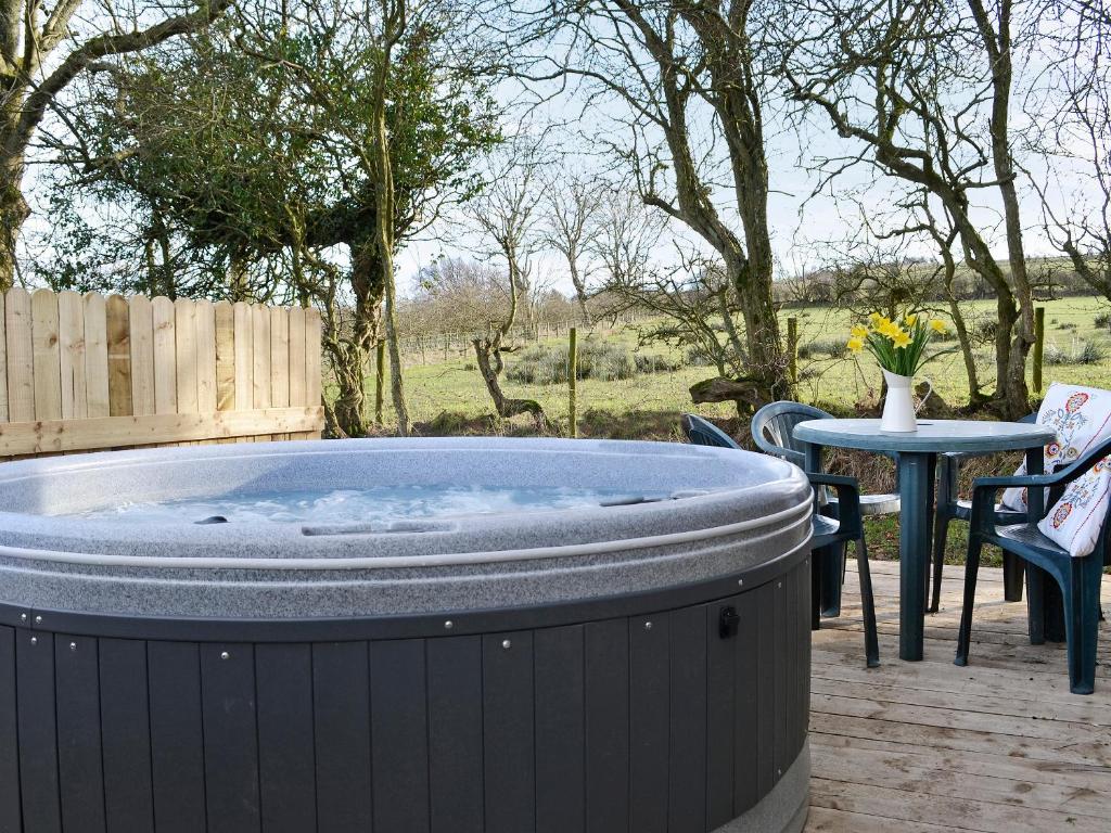 a hot tub on a patio with a table and chairs at Kestrel Cabin - Uk1246 in Westward