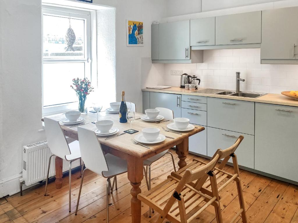 a kitchen with a wooden table and white cabinets at Nautilus in St Ives