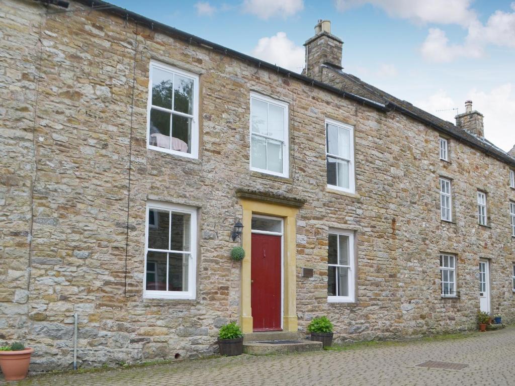 an old stone house with a red door at Gilmore House in Alston