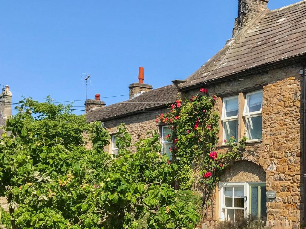 an old stone house with roses on the side of it at Lightfoot House in Redmire