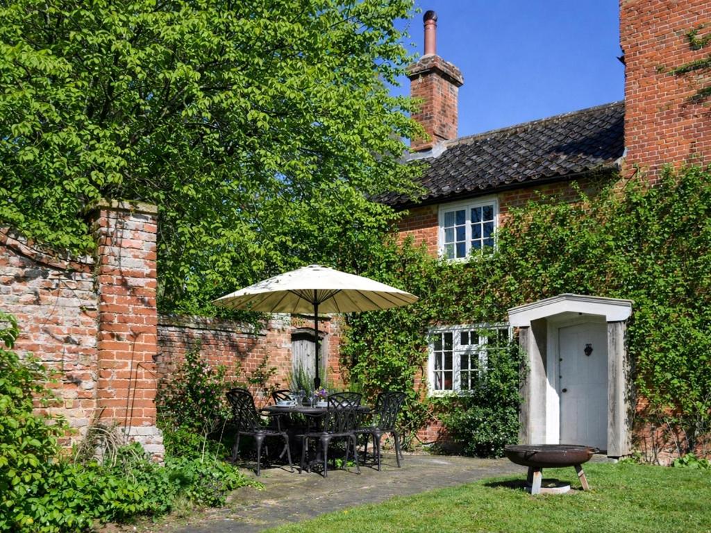 a house with a table and an umbrella and a grill at The Buttery in Buxton